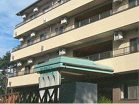 ベージュ色を基調とした４階建ての建物である。２階以上の階にはベランダがあり、周囲には木が植えられている。