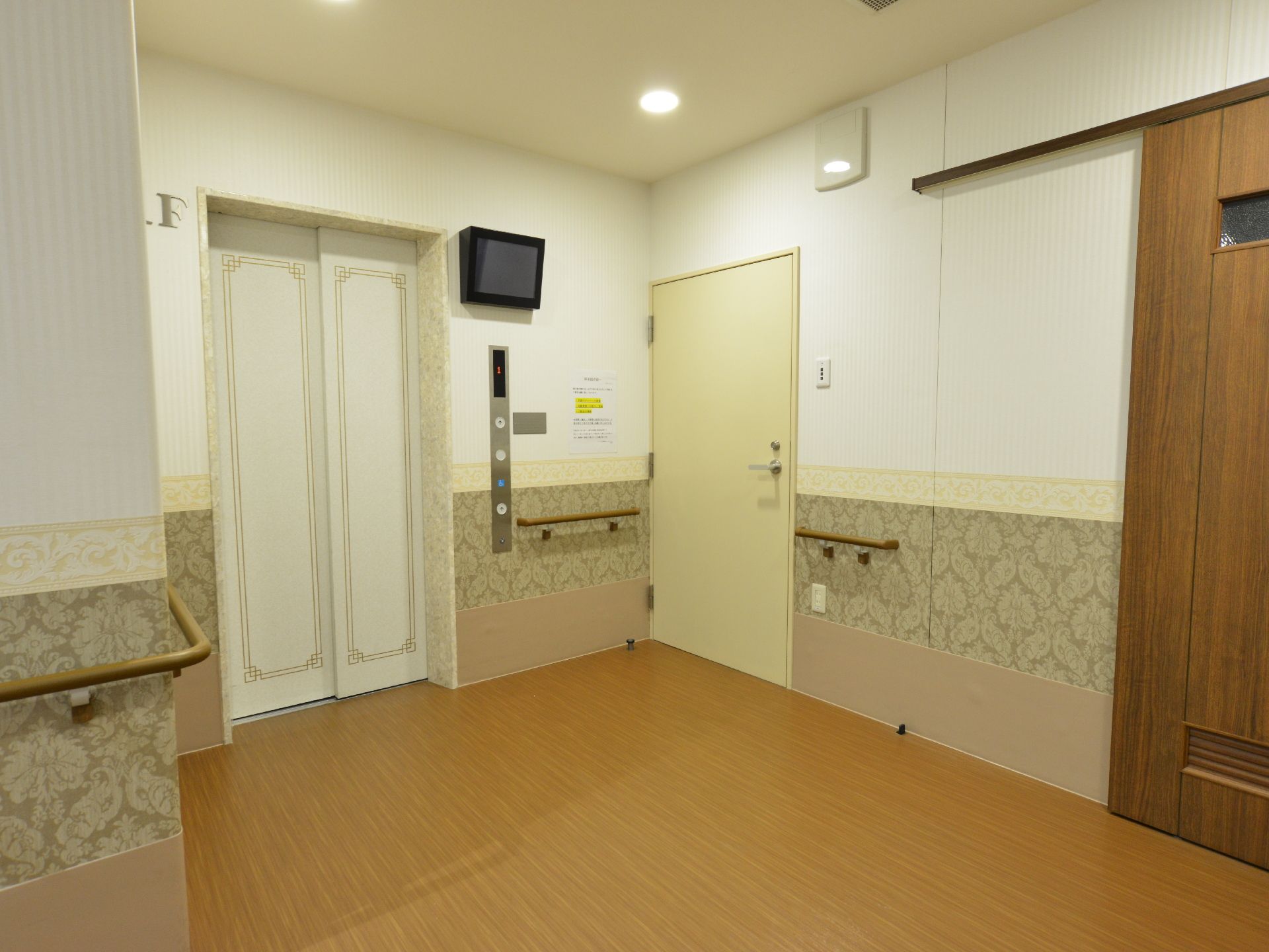 施設の廊下の一角には装飾箱のようなデザインのドアをしたエレベーターと、重い鉄扉で閉ざされた階段がある。