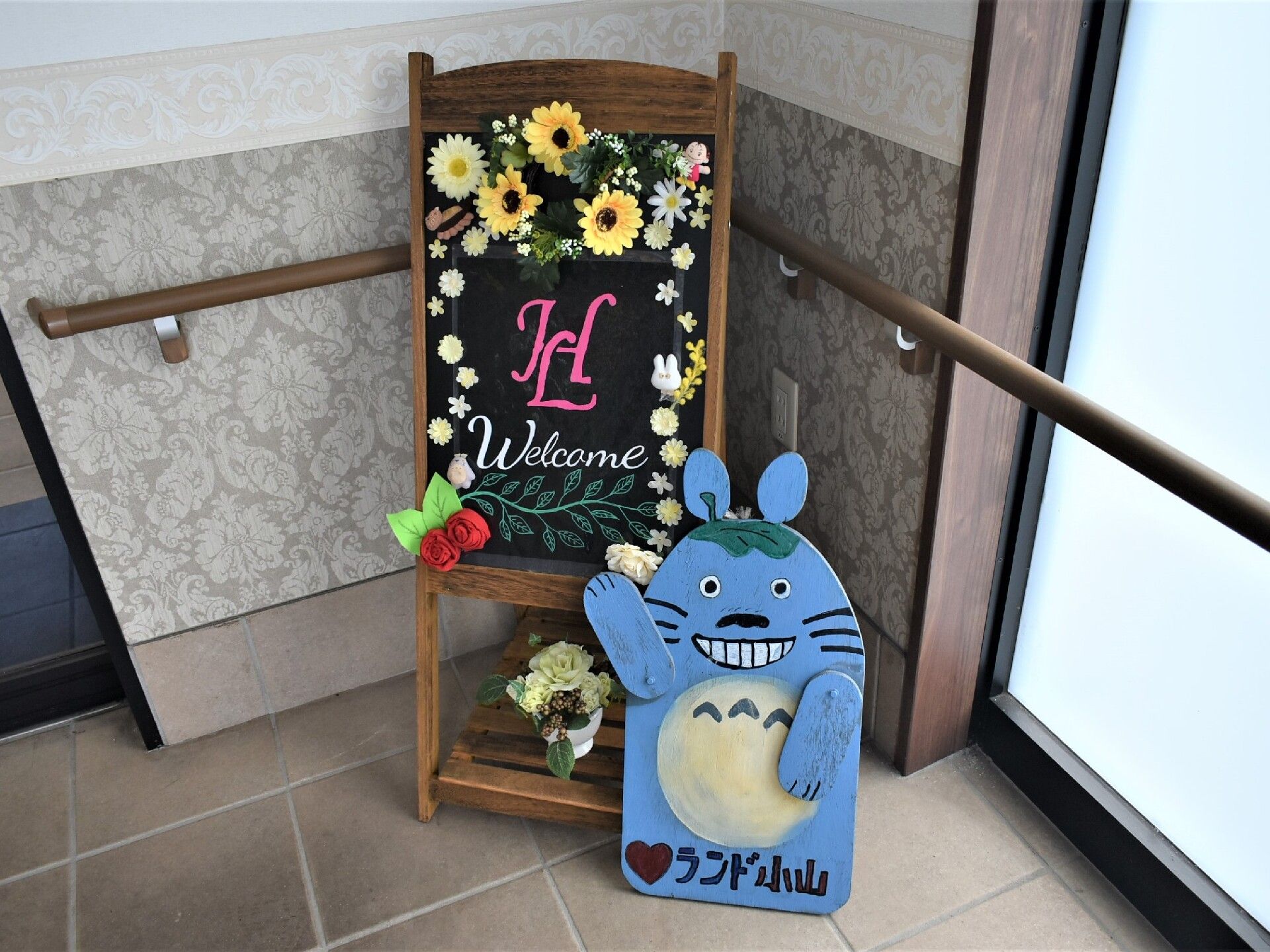 この施設に勤務して入居者の方々を支えるスタッフの方々の集合写真。シャツの上にエプロンを装着するタイプの制服になっている。