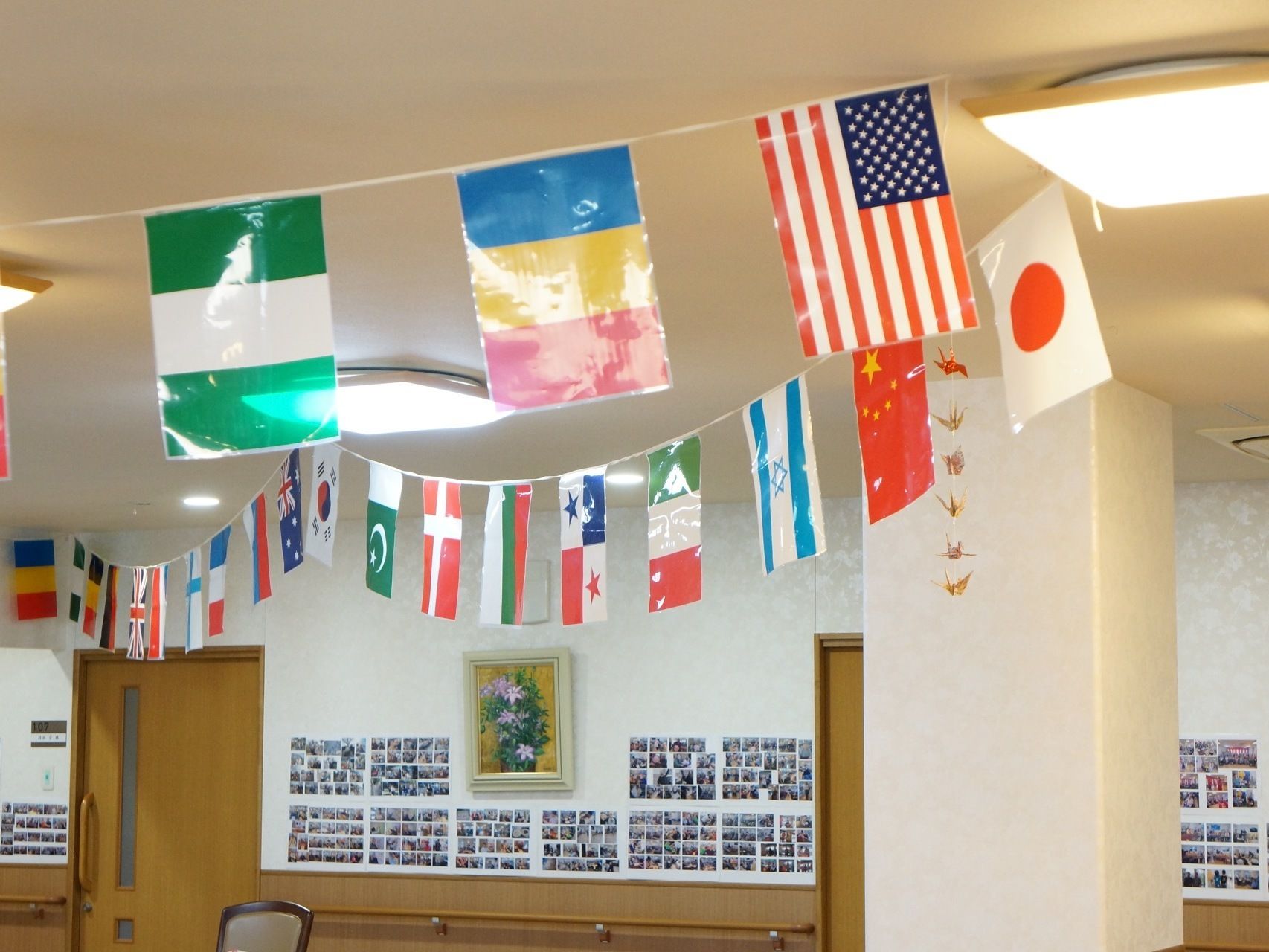 食堂の天井には世界各国の国旗が等間隔で掛かっている。壁には入居者様たちの写真がたくさん貼り付けられている。