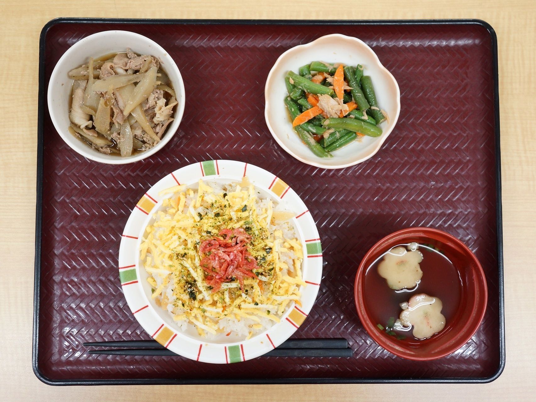 小豆色のお盆にはお箸と一緒に4品の食事が並んでいる。たまごと桜エビを乗せたごはん、お吸い物、牛蒡と牛肉のしぐれ煮、お吸い物である。