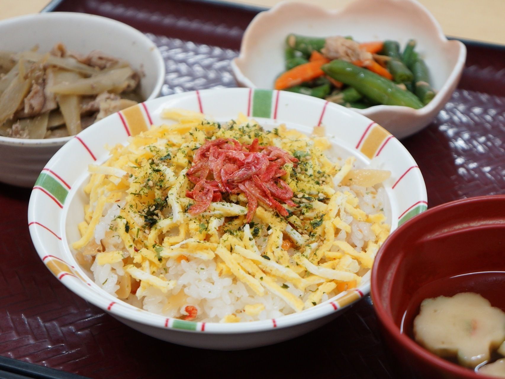 お盆にはご飯に卵や桜エビを乗せたものや牛蒡と牛肉のしぐれ煮、お吸い物、いんげんと人参の和え物が並んでいる。