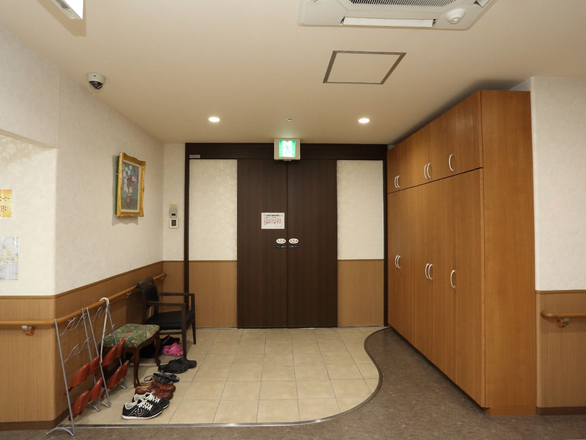 玄関には背の高い茶色い靴箱が置かれている。壁側には手すりが取り付けられていて、靴ベラが掛けられている。椅子も用意されている。