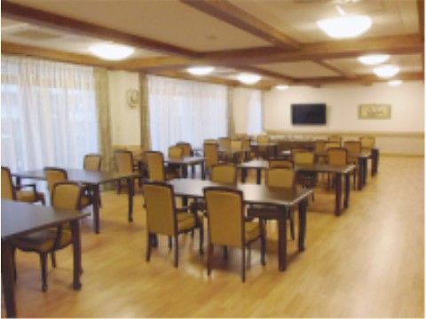 広々とした和テイストの大食堂で、茶色の落ち着いたダイニングセットが配置されている。大型テレビを完備している。