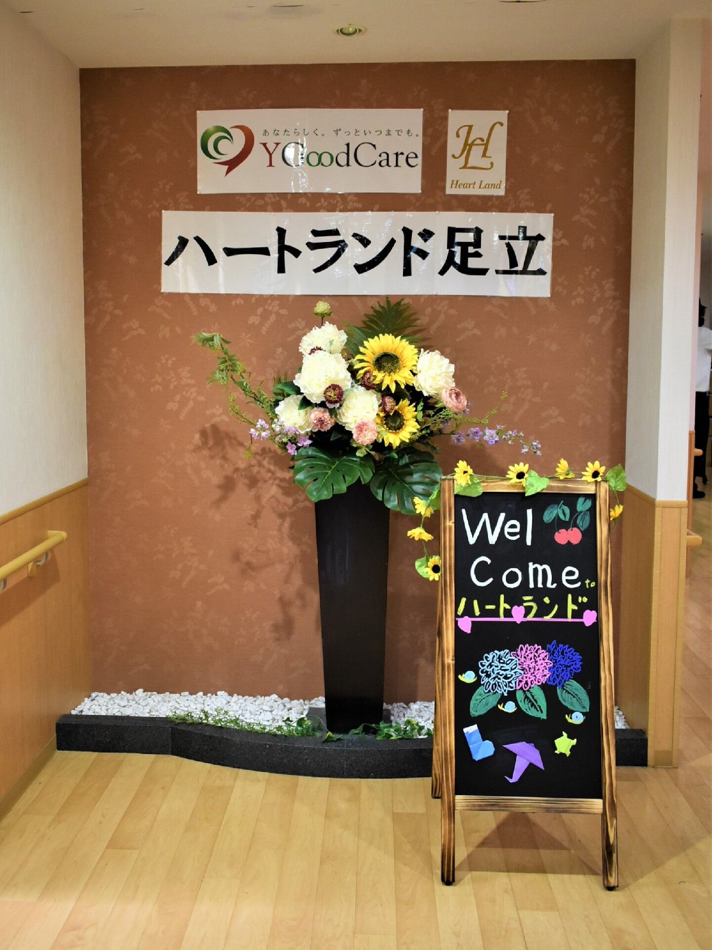 大きなフラワーアレンジメントが飾られたエレベーターホール。エレベーター横上部にはモニタが備え付けられている。