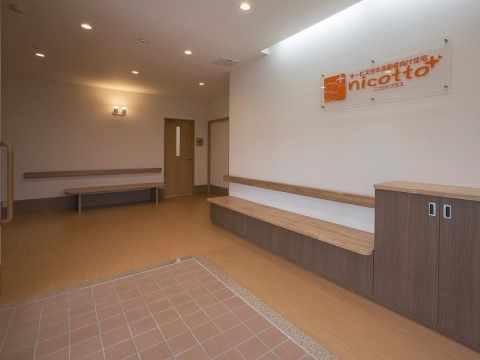 バリアフリー構造の玄関。壁には手すりが付けられ、作り付けの靴箱とベンチがある。