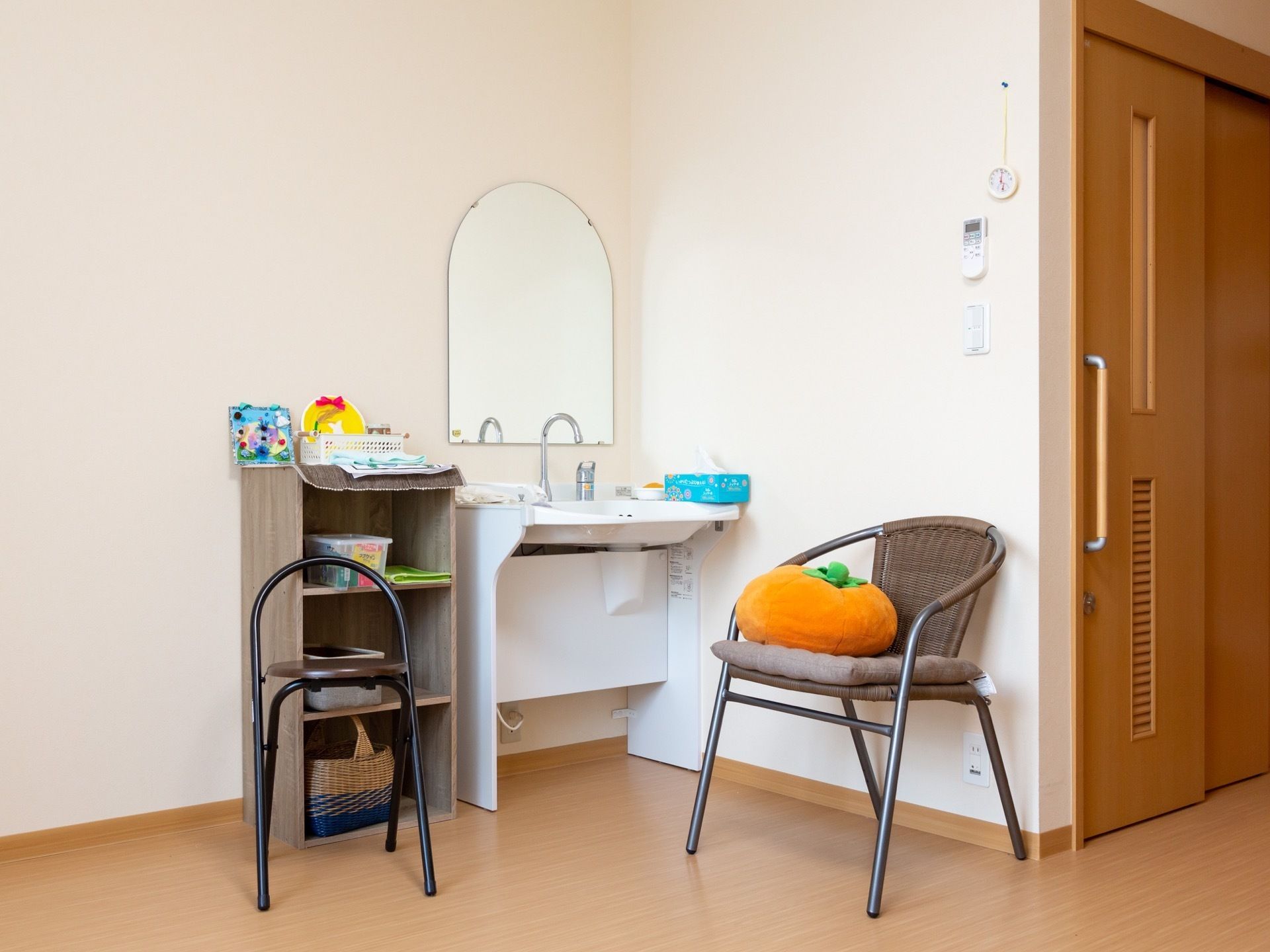 居室のトイレのそばには鏡と洗面台が用意されている。そのまわりには、椅子や棚、さまざまな小物が置かれている。
