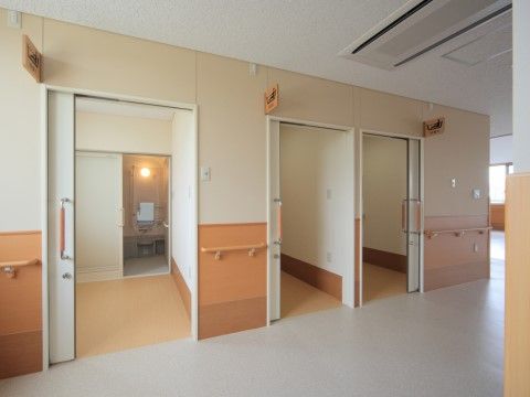 窓のある明るい廊下に並んだ個別浴室。引き戸になった大き目の入口の奥には広い脱衣所があり、一番奥に浴室がある。