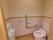 ピンク色のタイルと同色の便器で揃えたトイレである。便器には温水洗浄便座が付いている。また、手洗い用の水栓が設置されている。