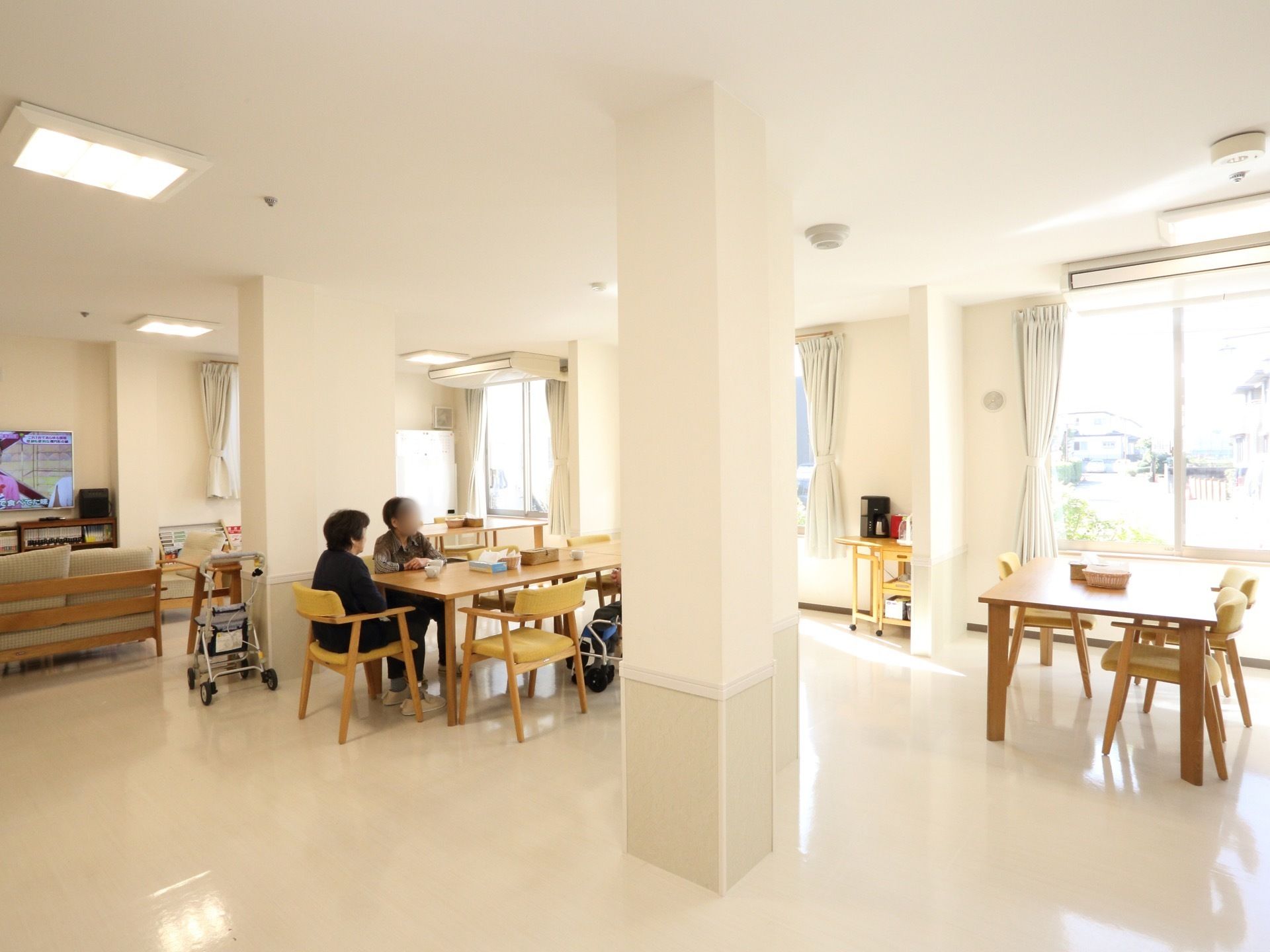 複数の入居者様が食堂で談笑をしている。食事の時間以外も利用ができ、自然光もよく当たる。日光浴にも使用できる。