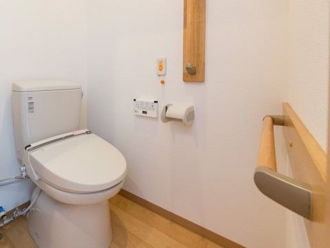 ナースコールや温水洗浄便座が設置された機能的なトイレである。手すりも設置し、安全にご利用いただける。
