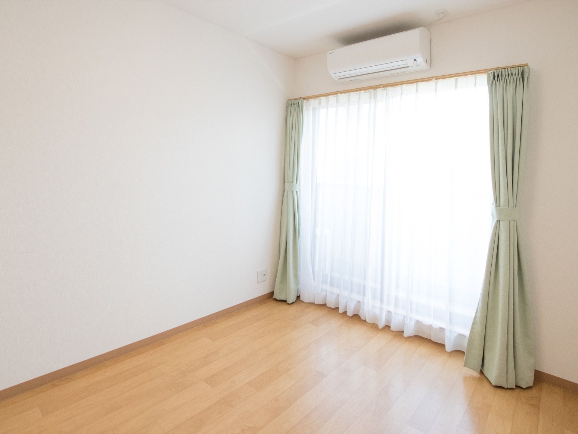 居室には大きな窓から十分に光が入り、壁紙も白で統一されているため、明るい雰囲気の部屋になっている。窓上部にはエアコンが備え付けられている。