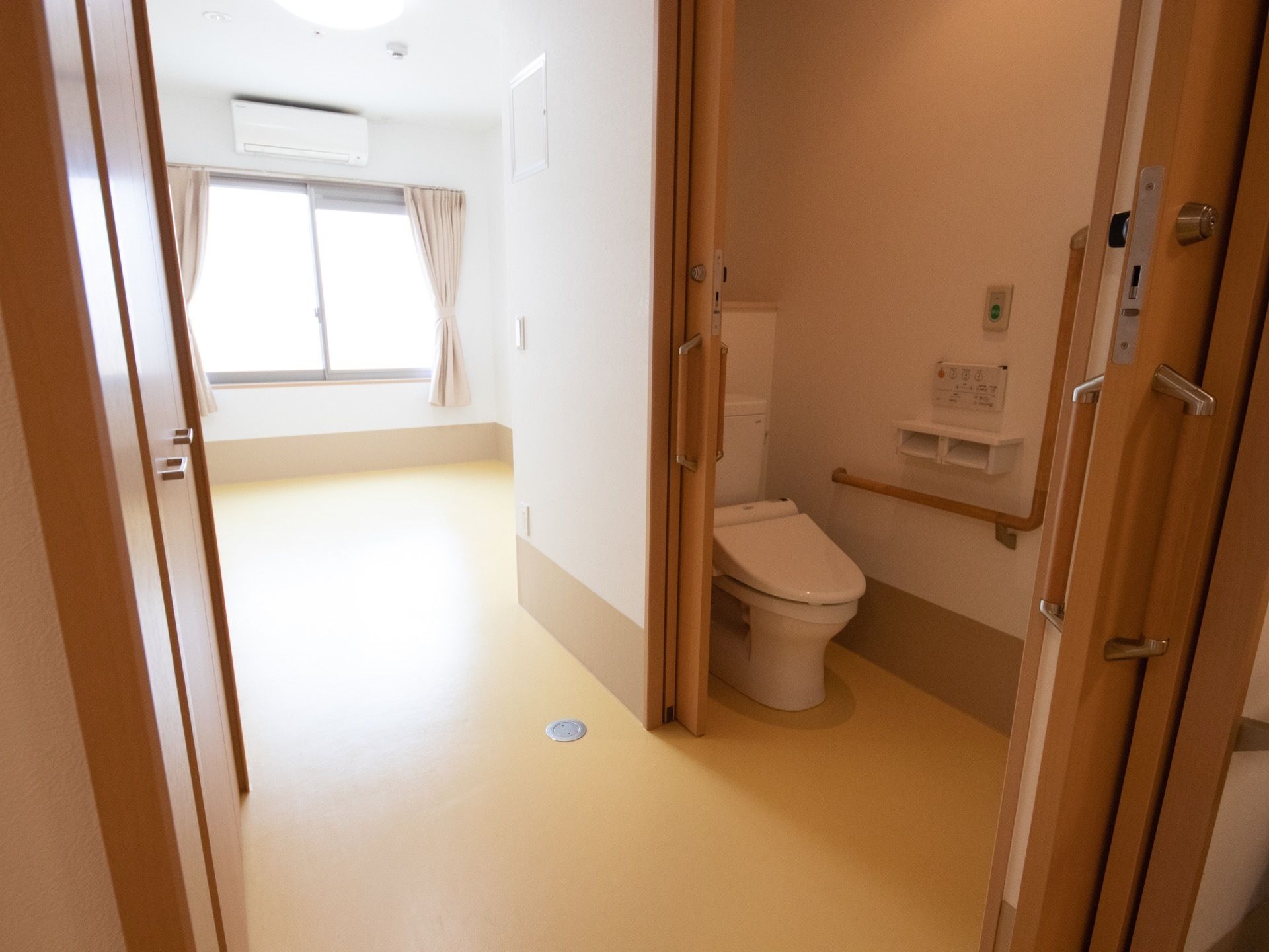 居室の中にトイレが備え付けられている。手すりに緊急用ボタンが設置されているので、室内で緊急時にも安心できる造りになっている。