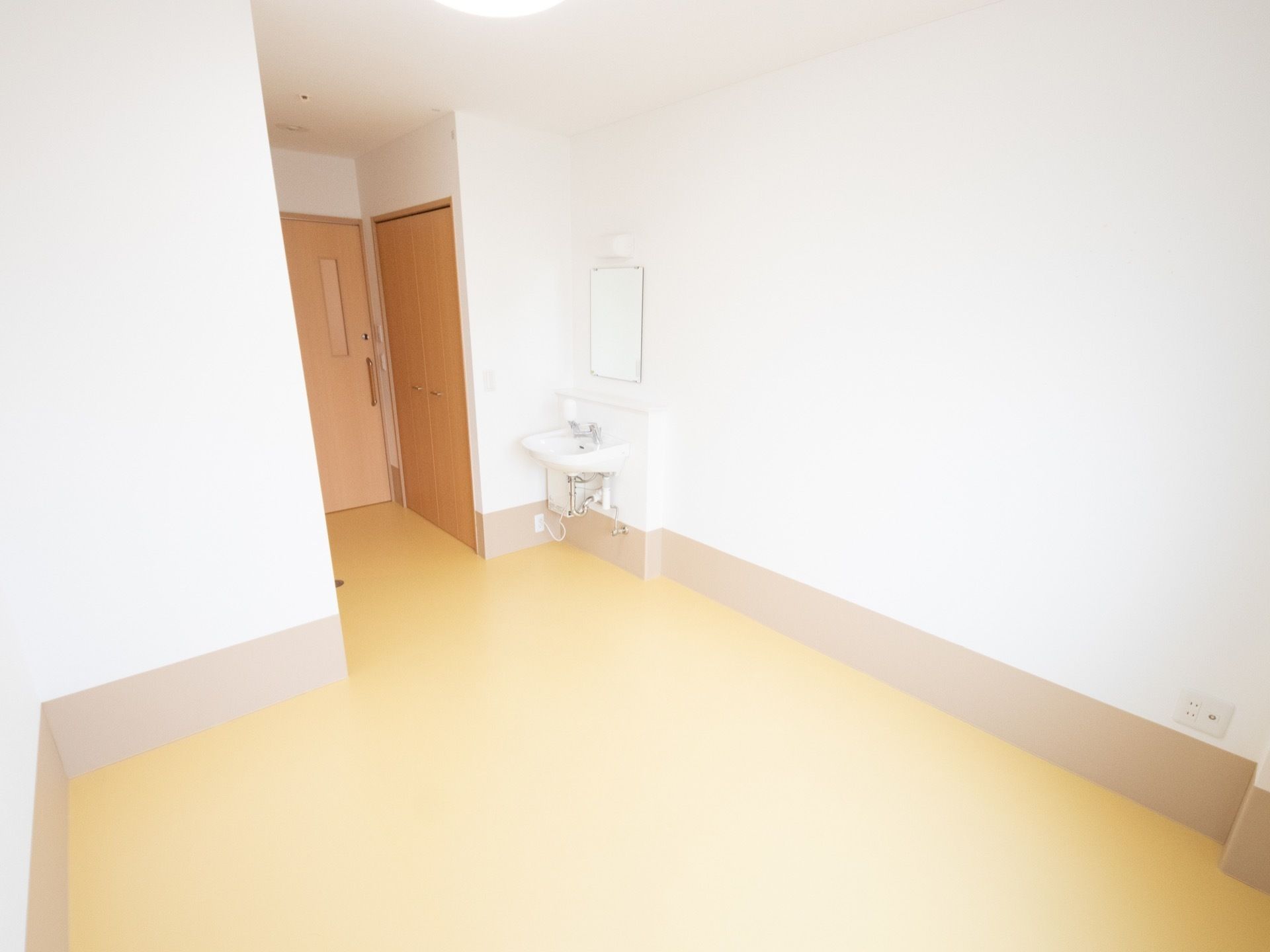 居室の入り口から、部屋の中までは障害や角もなく真っ直ぐに移動ができる。窓から日が差す、明るい室内となっている。