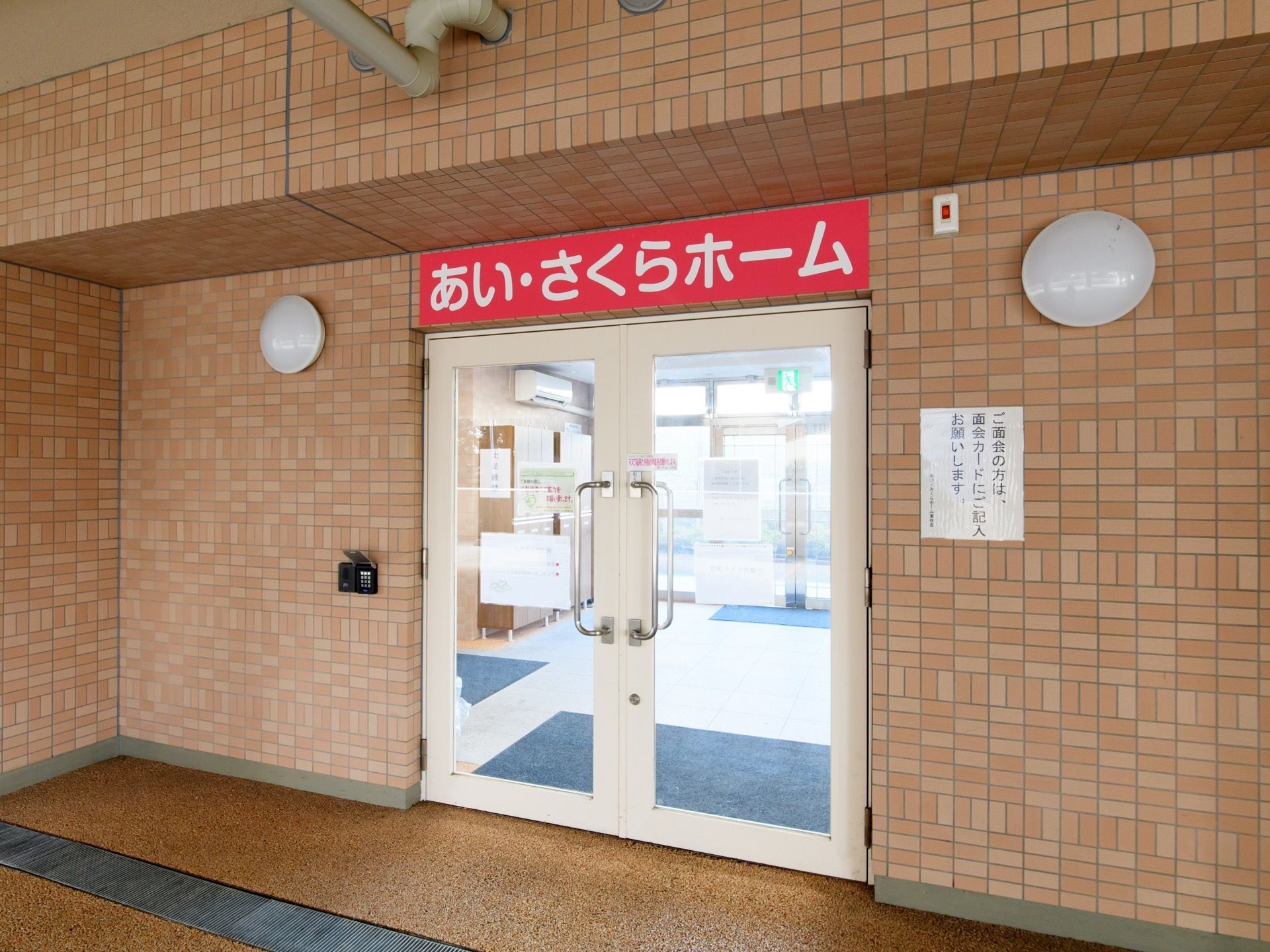 玄関には、施設名が大きく書かれた看板が設置されている。中へ入る際には受付を通る必要があり、不法侵入を防ぐ目的でも安心感がある。
