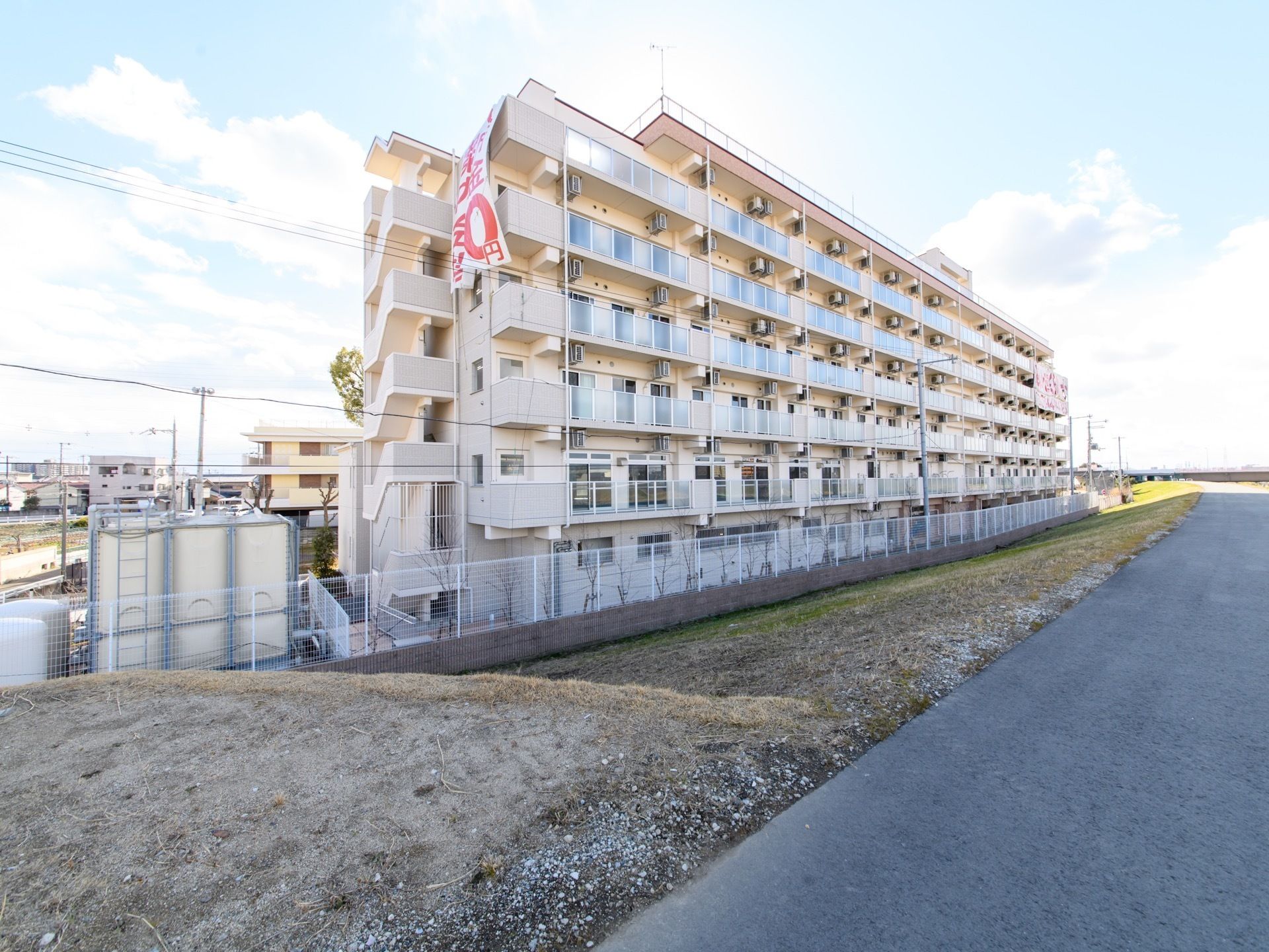 土手から見える建物は、一見すると大きなマンションに見える。6階建てで非常に大きく、白を基調として作られている。