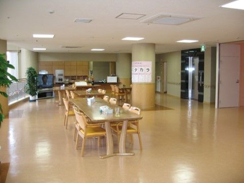広いスペースにダイニングテーブルと椅子が並べられている。カウンターがあり、その側には大型テレビが置かれている。