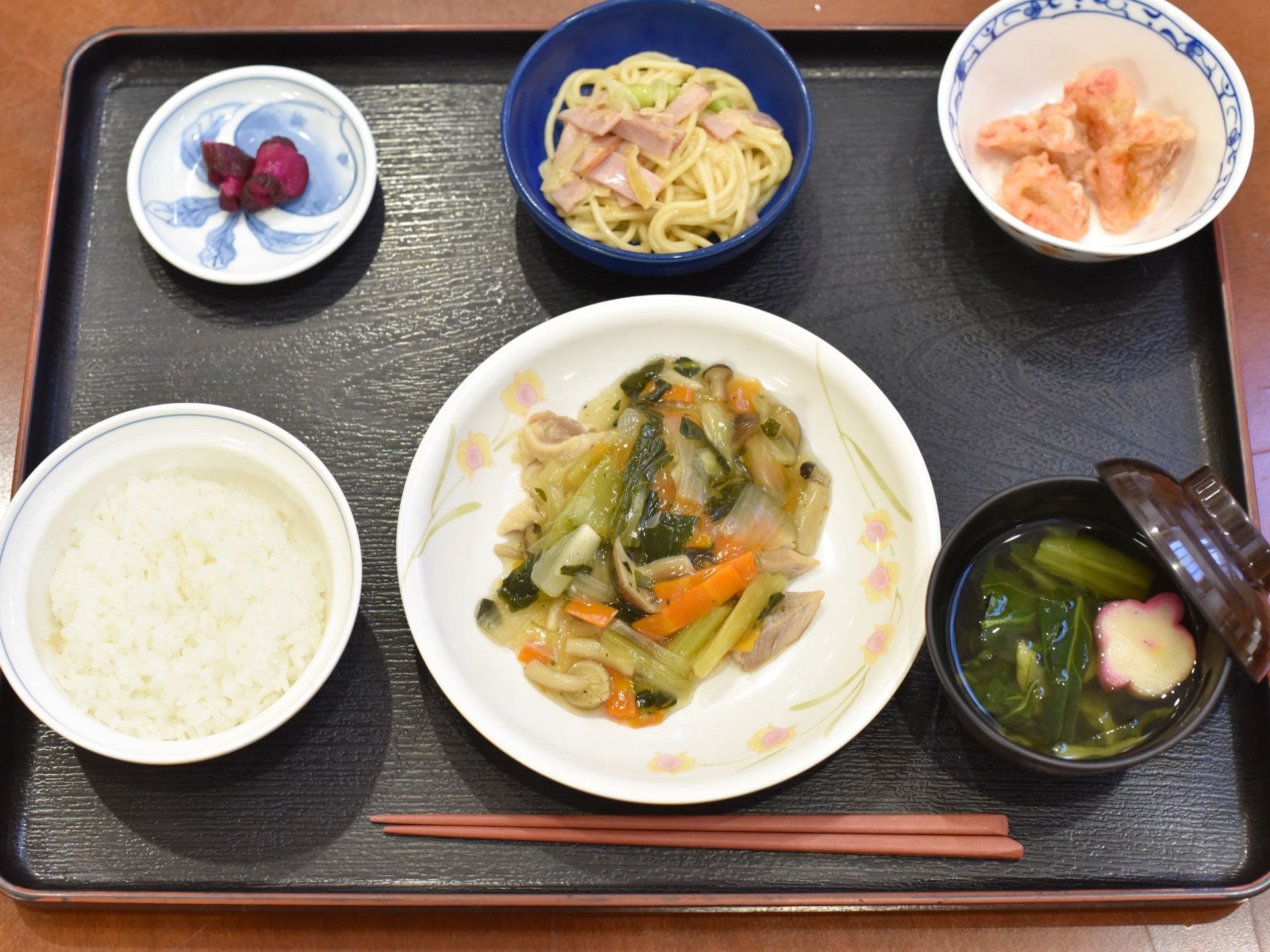 ご飯とお吸い物に八宝菜のメインおかずと小鉢が２つにお漬物が添えられた食事である。彩りに工夫されている。