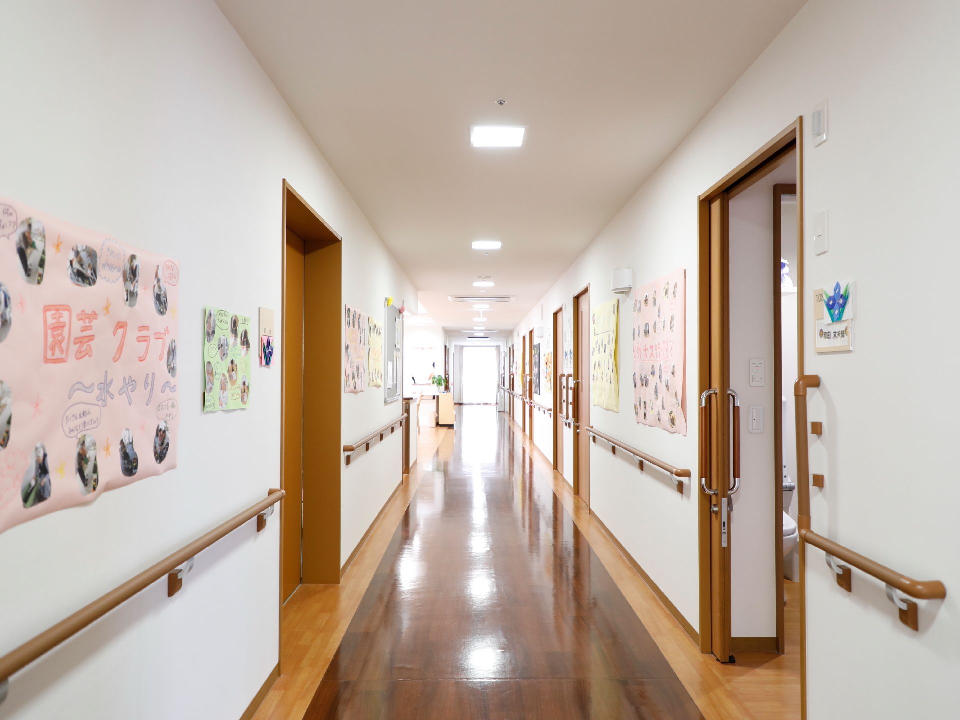 利用者様の各部屋の扉は、横に開閉するスライド式になっている。壁には利用者様の制作作品や写真が掲示されている。
