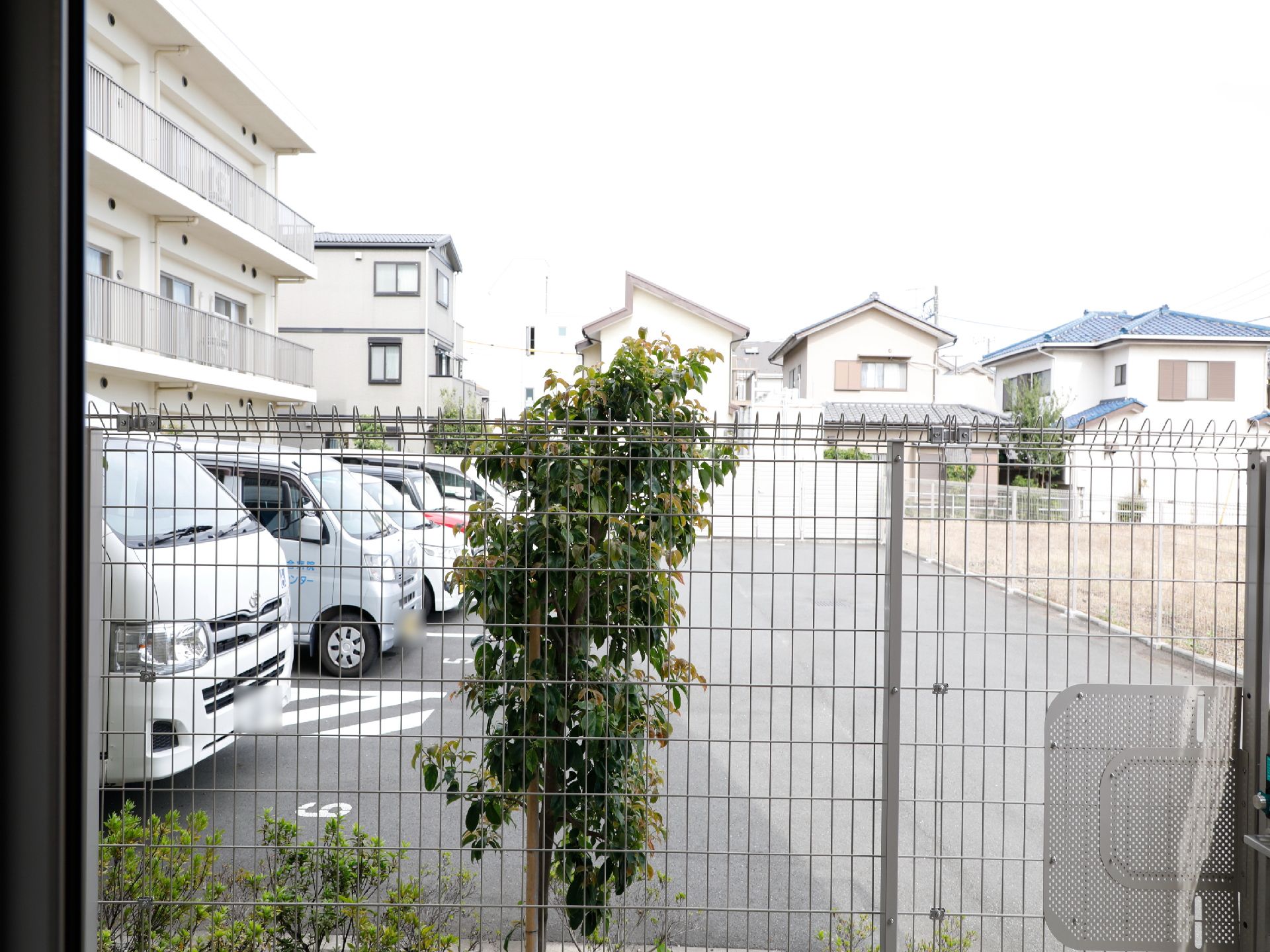 施設の敷地周囲には柵が取り付けられている。駐車スペースは敷地外になっている。柵の外側でも植物を育てている。