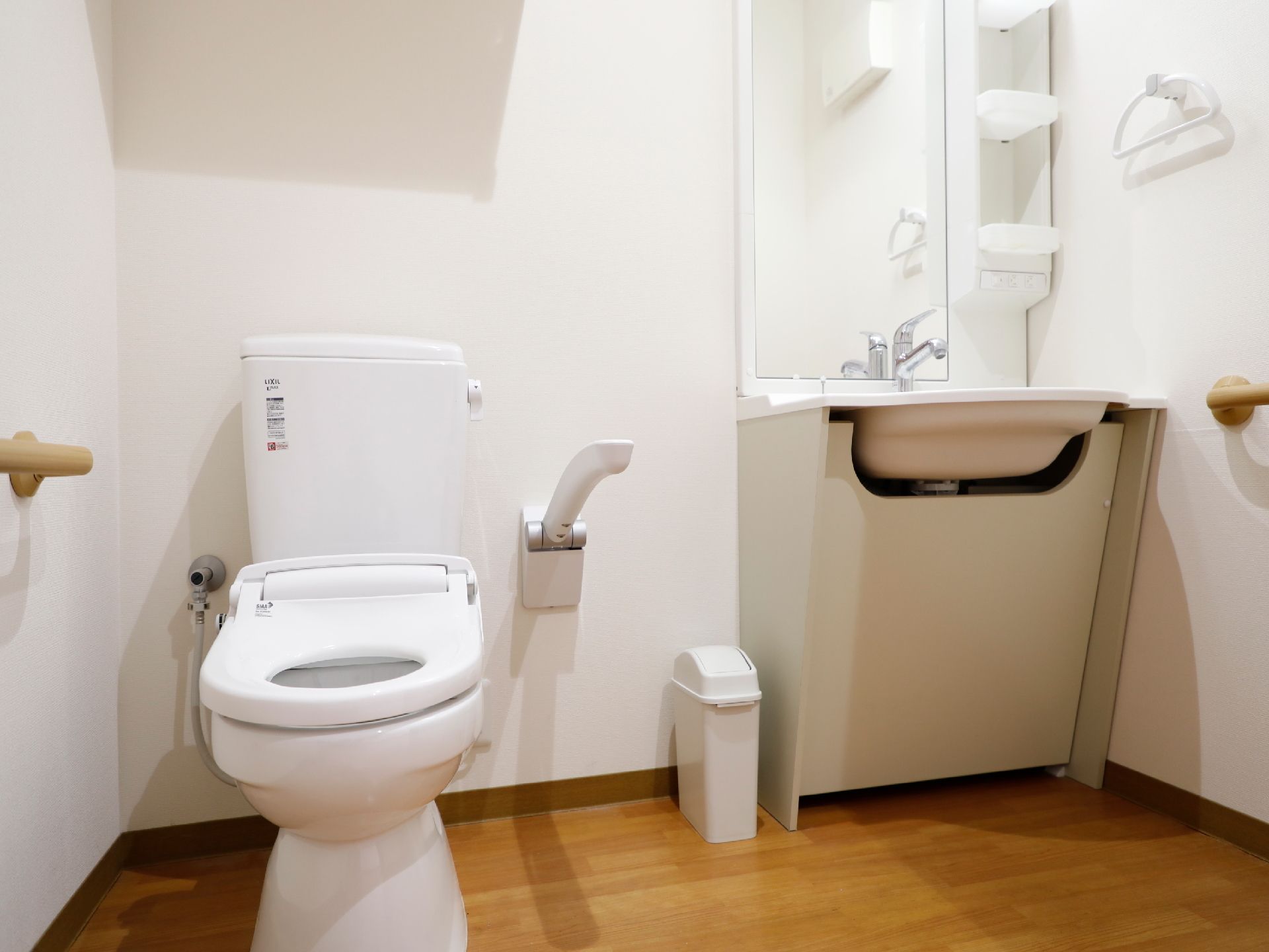 洋式のトイレで、壁には手すりが取り付けられている。反対側は上下に稼働する手すりも取り付けられている。