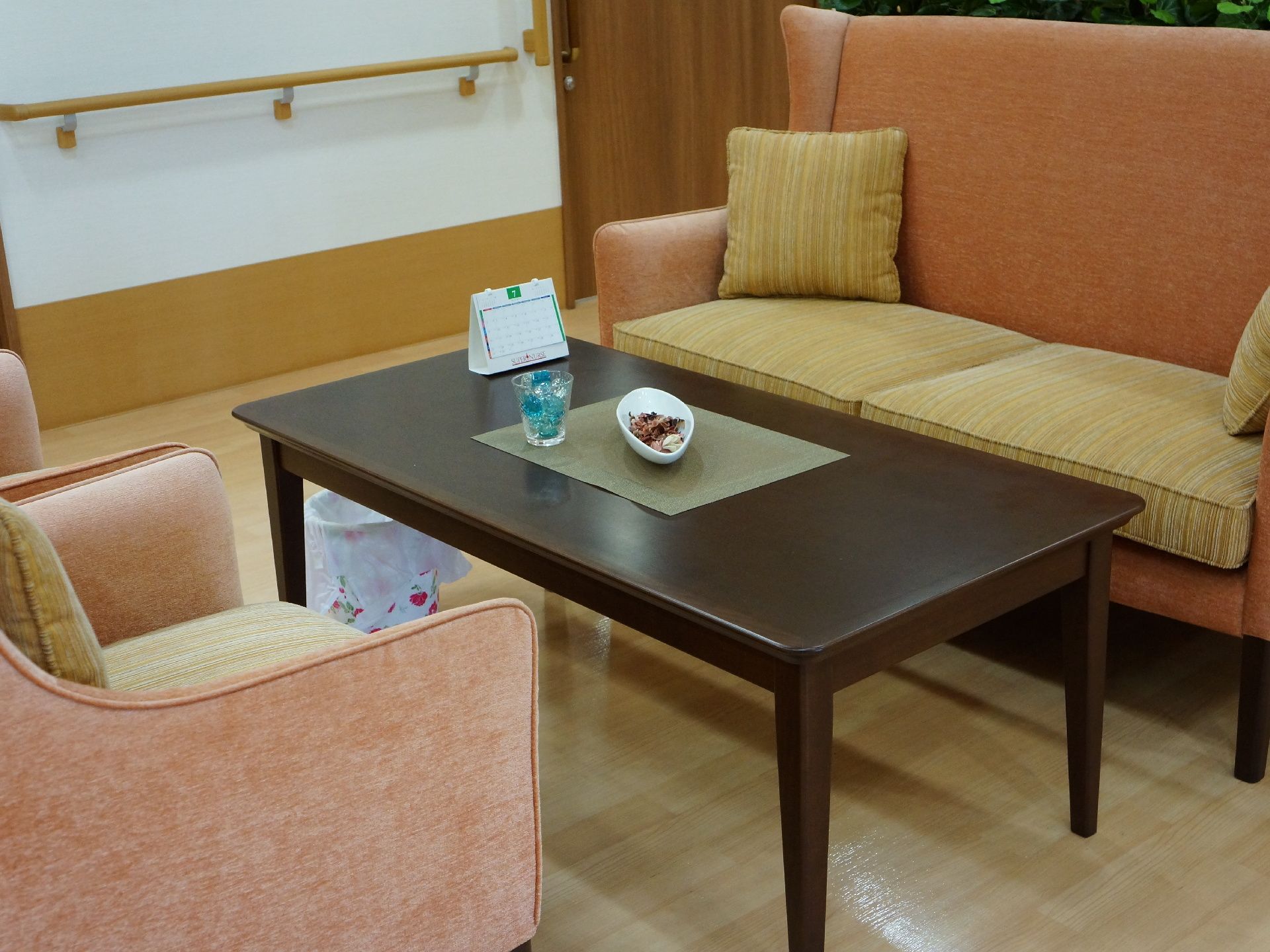 応接セットは4人用で、木製のテーブルに、2人掛けのソファー、1人掛けの椅子2個がある。各ソファーと椅子にはクッションが置かれている。