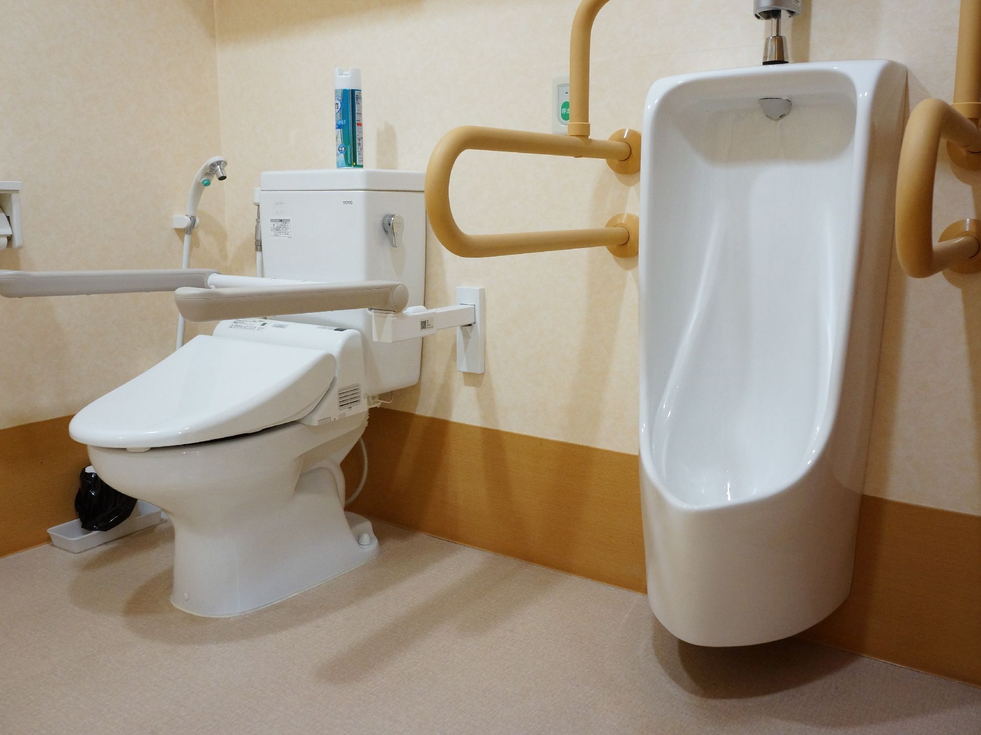 広いスペースに男性用小便器と、様式トイレが設置されている。それぞれ小便器の両側、便器の両側には手すりが付いている。