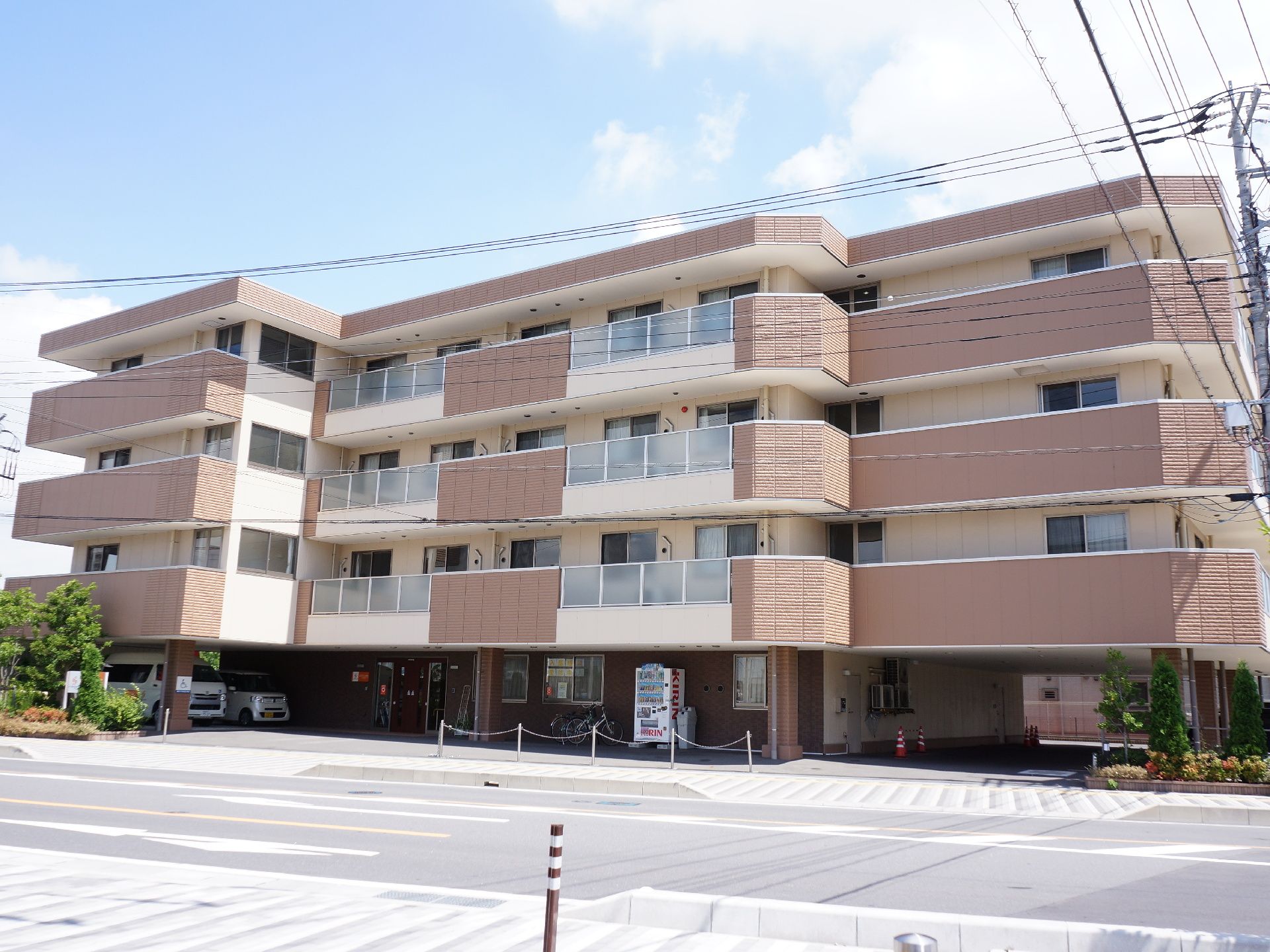 建物は4階建てで、ベージュとブラウンのツートンカラー。1階部分は少し奥まったところにあり、屋根がかかった形になっている。