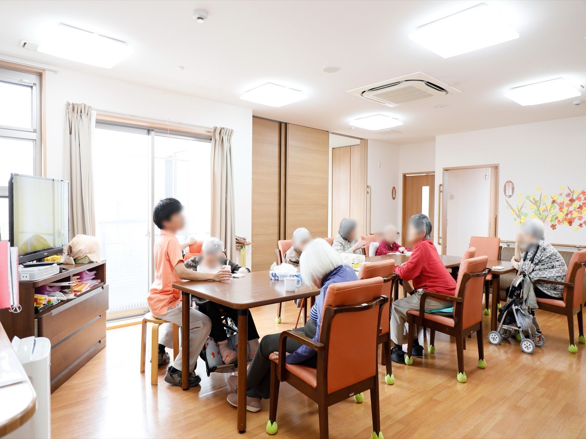 テレビのある共有部屋では、テーブルセットをつなげて8名以上で席につくことができる。壁際にはソファー席もある。