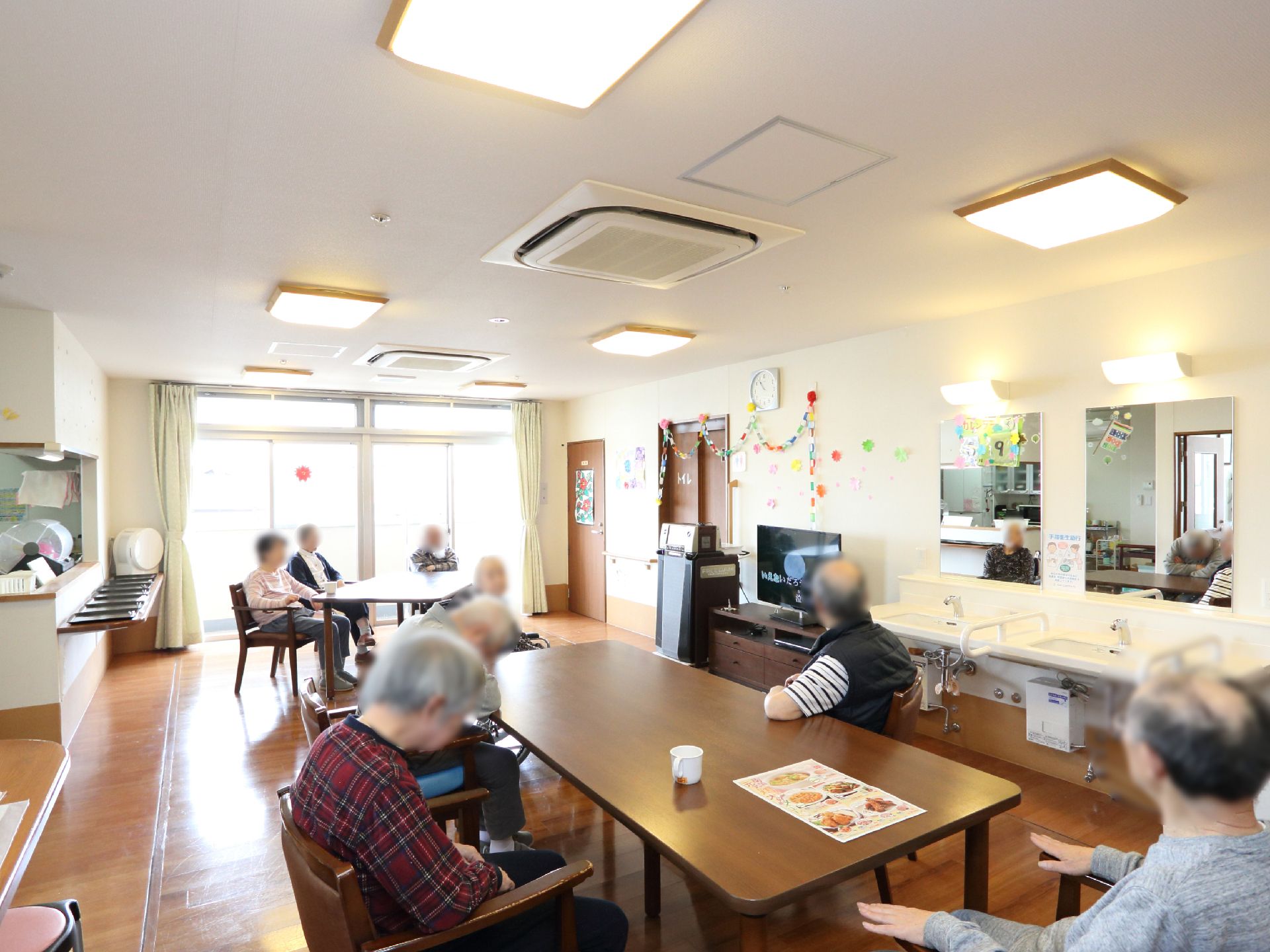 食堂の奥には、光の差し込む大きな窓が取りつけられている。中央には、入居者が利用する長テーブルと椅子が並べられている。