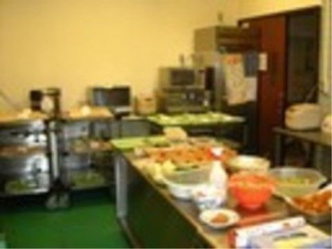 壁側には電子レンジや炊飯器などの家電がきれいに置かれている。調理台は食事準備中で、さまざまな色合いの食材が容器に入っている。
