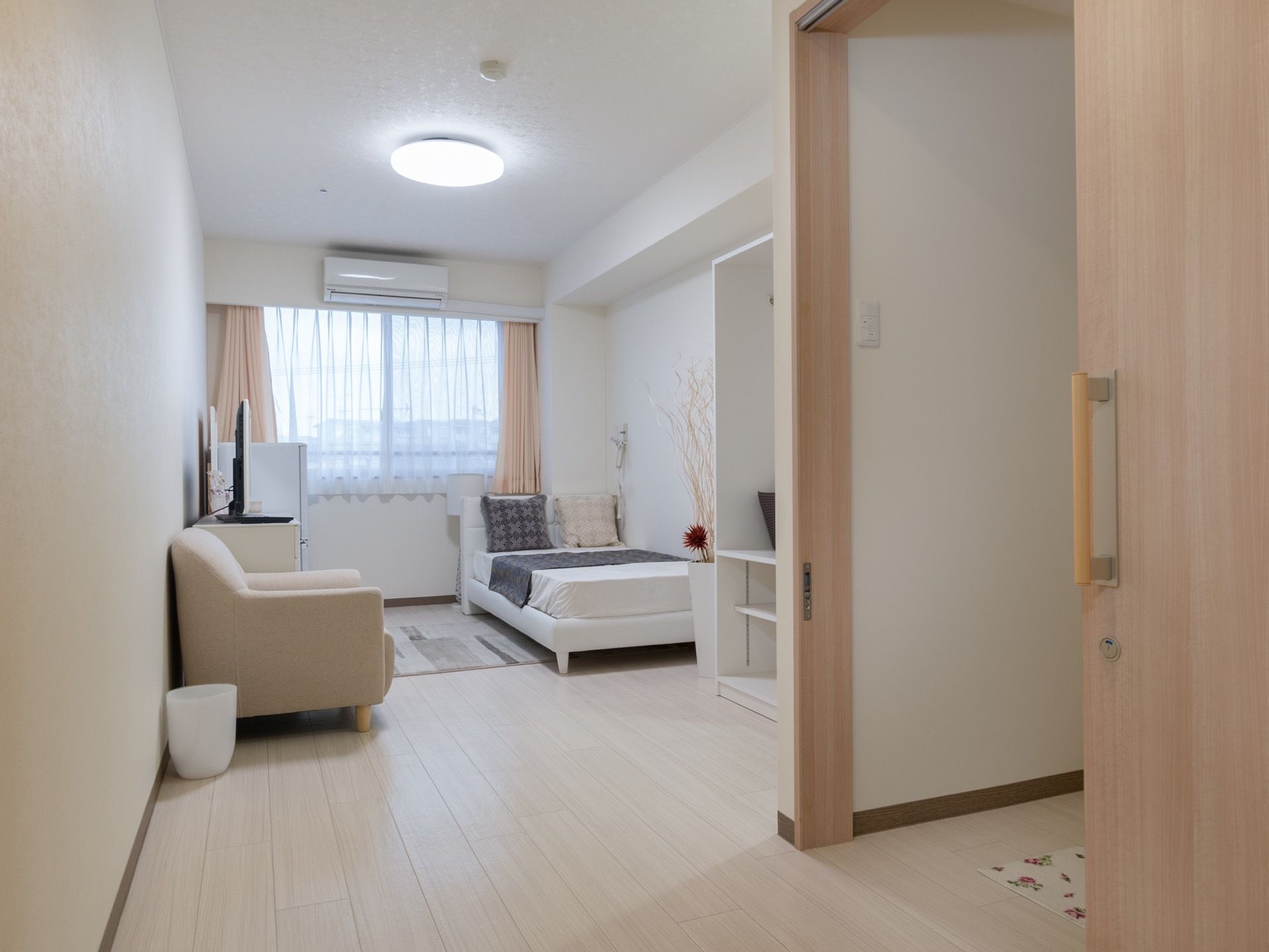 居室にはベッドがあり、ソファやローチェストが置かれている。また壁には窓があり、エアコンを備え付けている。