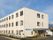 アイボリーの外壁で明るい雰囲気の３階建ての建物である。玄関には屋根が付いているので、雨の日でも安心して車の乗降ができる。