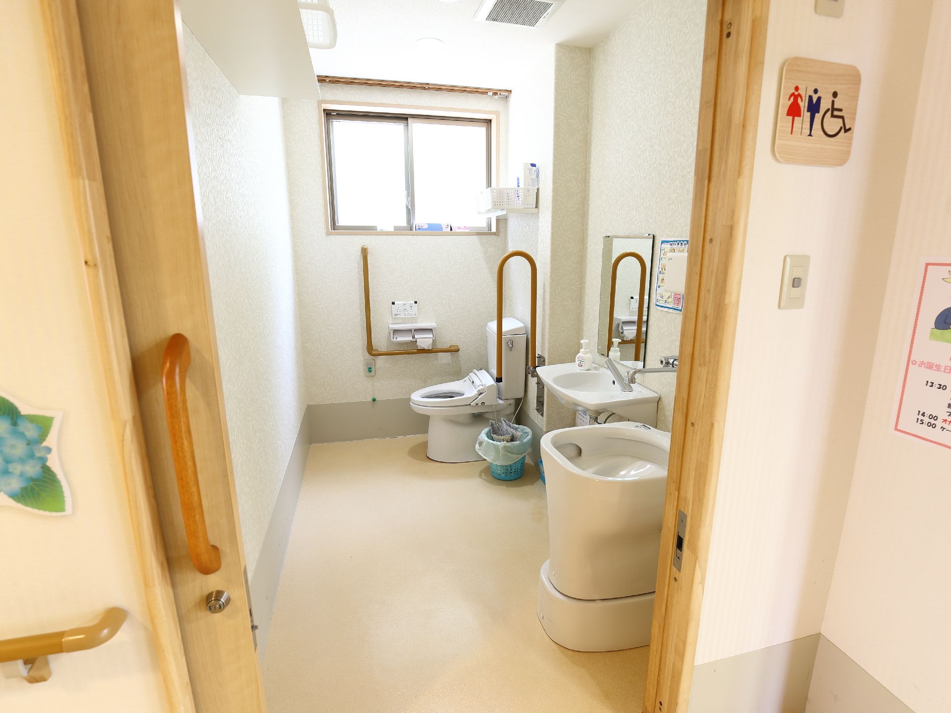 トイレのドアはスライド式で、ドアの横に男女車椅子利用可能の表示がある。一番奥に洋式便所があり、手前にオストメイトの設備がある。