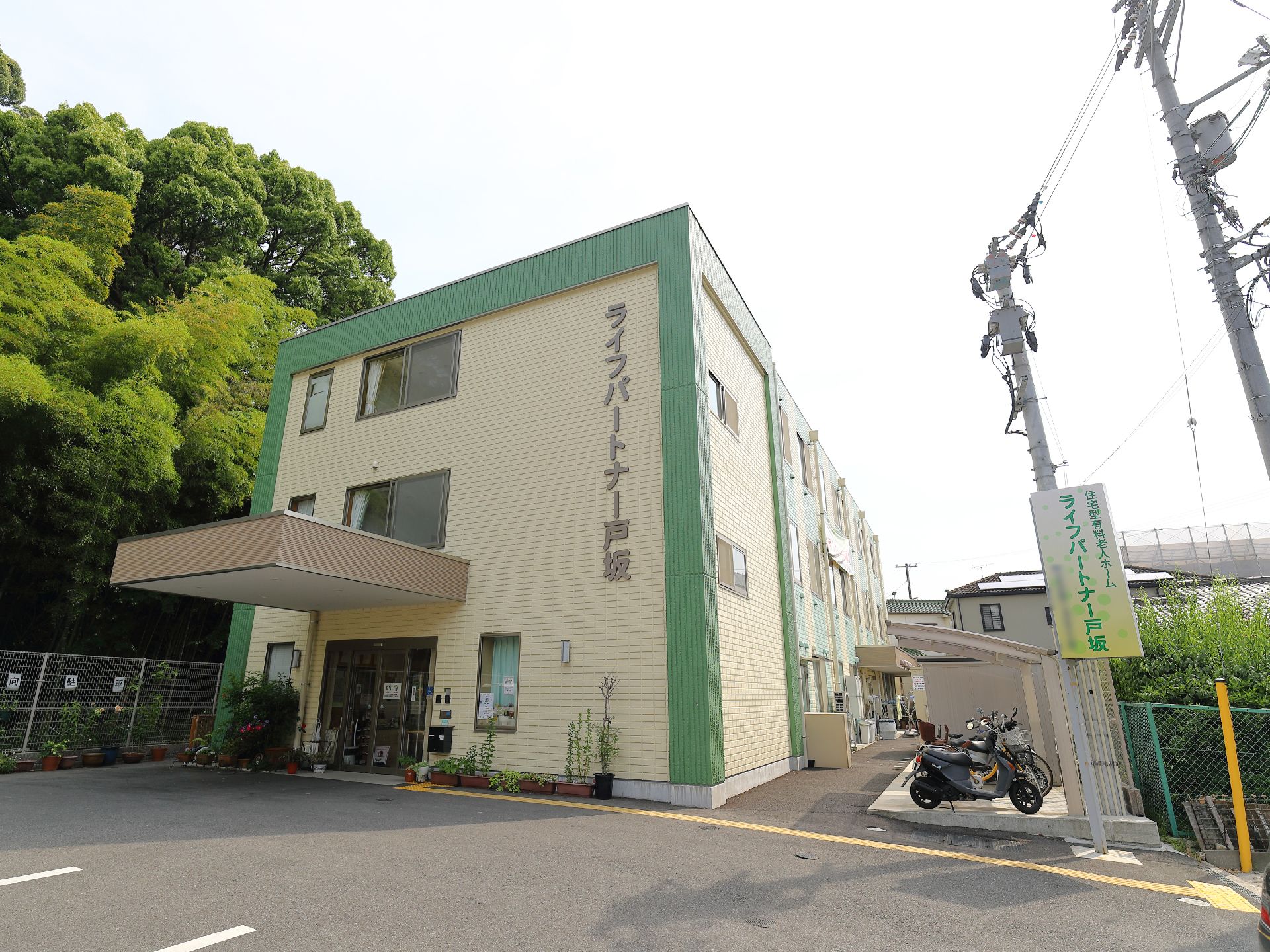 施設出入り口に向かって左側には竹林がある。右側には駐輪場があり、自転車、原付バイクなどをとめることが可能。駐車場も複数台ある。