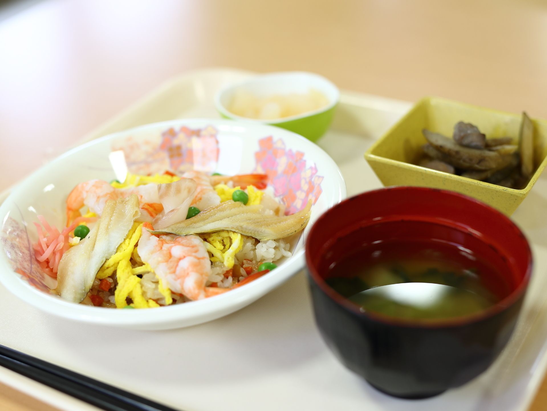 一人分の食事が、お盆にのって配膳されている。エビやアナゴの乗ったちらし寿司に、汁椀と小鉢、デザートも付いている。