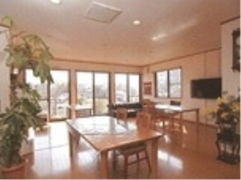 窓やサッシが多く、開放的な雰囲気のロビー。手前にテーブルセットがあるほか、奥の窓際にはソファーも置かれている。