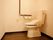 居室備えつけのトイレ。右手側の壁には、手すりと一体になったデザインのトイレットペーパーホルダーとナースコールがある。