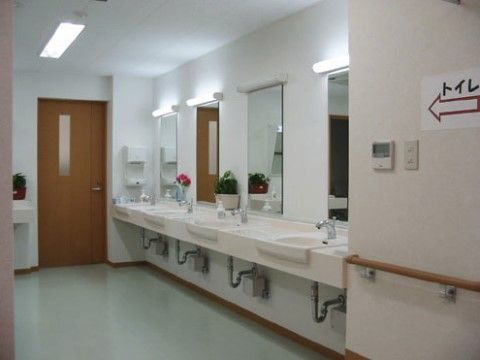 右側には洗面台と鏡が4つ並び、奥にはトイレの入り口扉