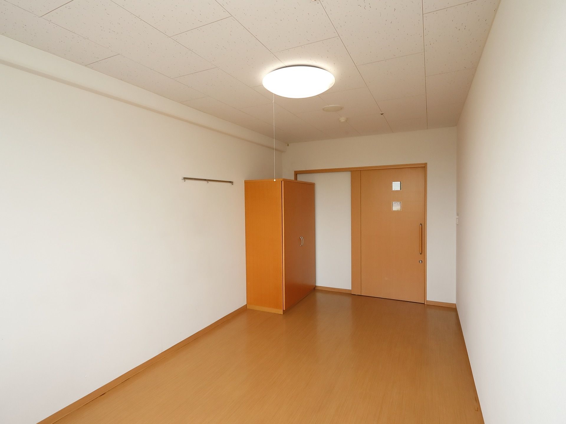 奥行きのあるフローリングの部屋がある。観音開きで木製のクローゼットが1つ置かれている。扉は引き戸になっている。