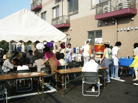駐車場にテントをたて、飲み物を飲みながら歓談する人達