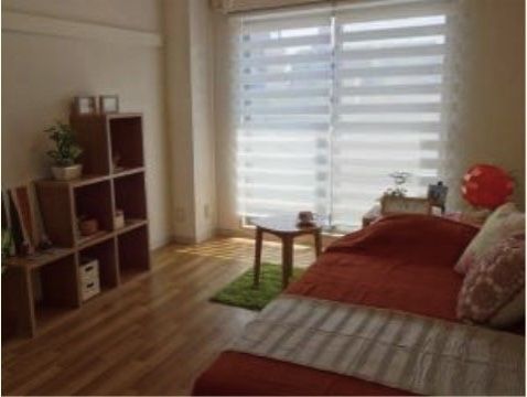 木目調の床におしゃれなミニカーペットやミニテーブル、棚があるベッド付き個室