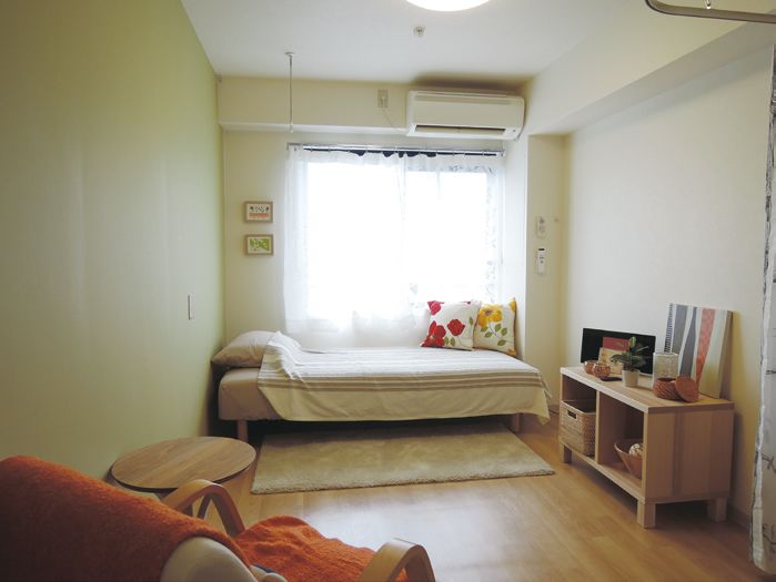 木目調の床におしゃれなミニカーペットやミニテーブル、棚があるベッド付き個室