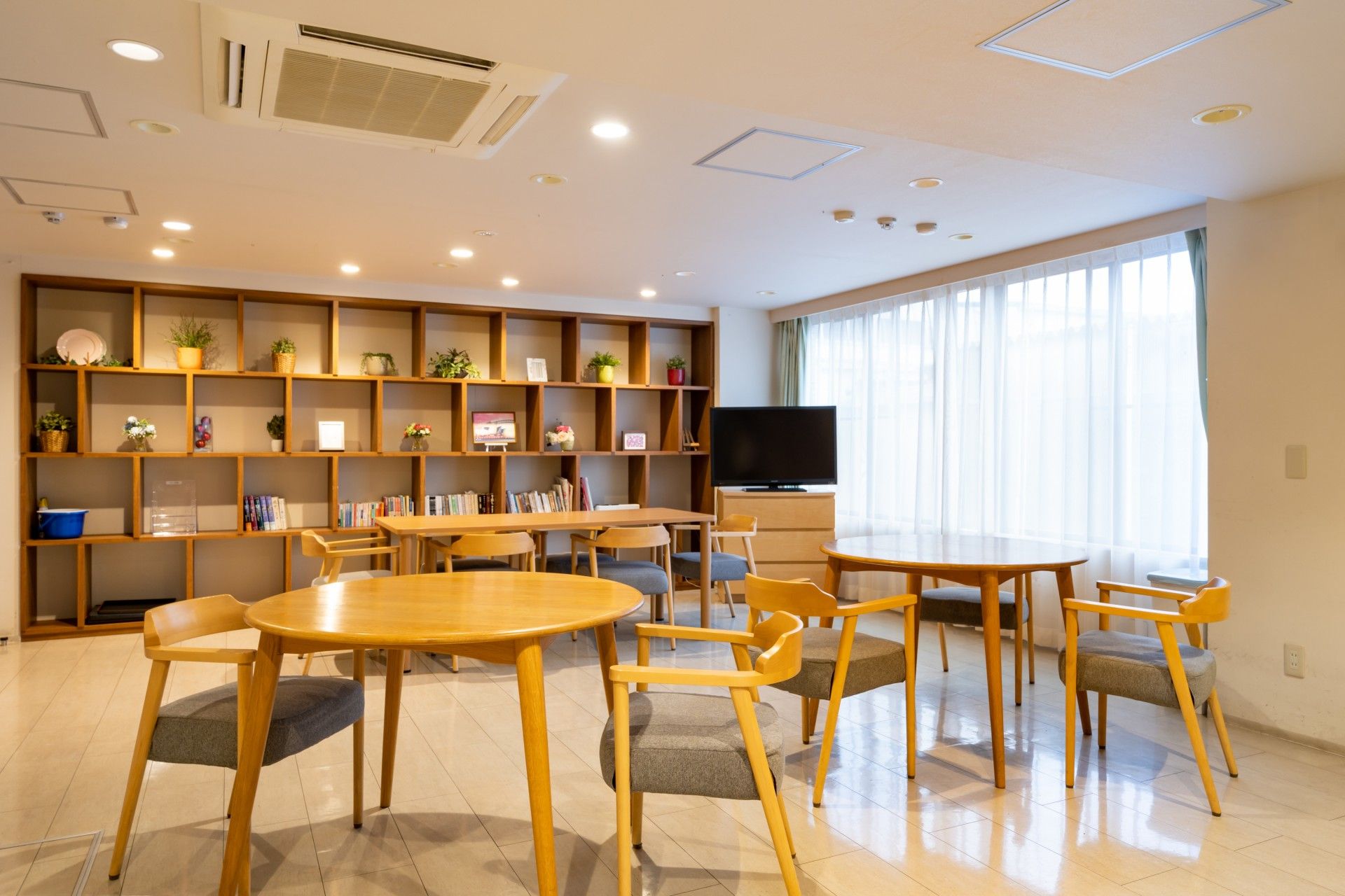 丸いテーブルを囲み、ピースサインで手をあげ楽しむ入居者とスタッフ