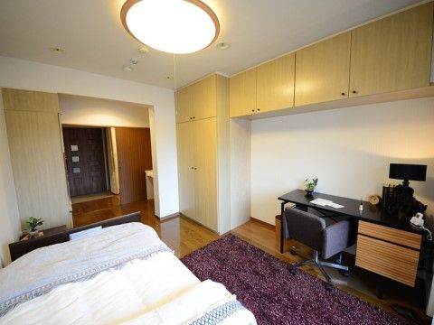 ベッドの横に紫色のカーペットが敷かれているおしゃれな居室