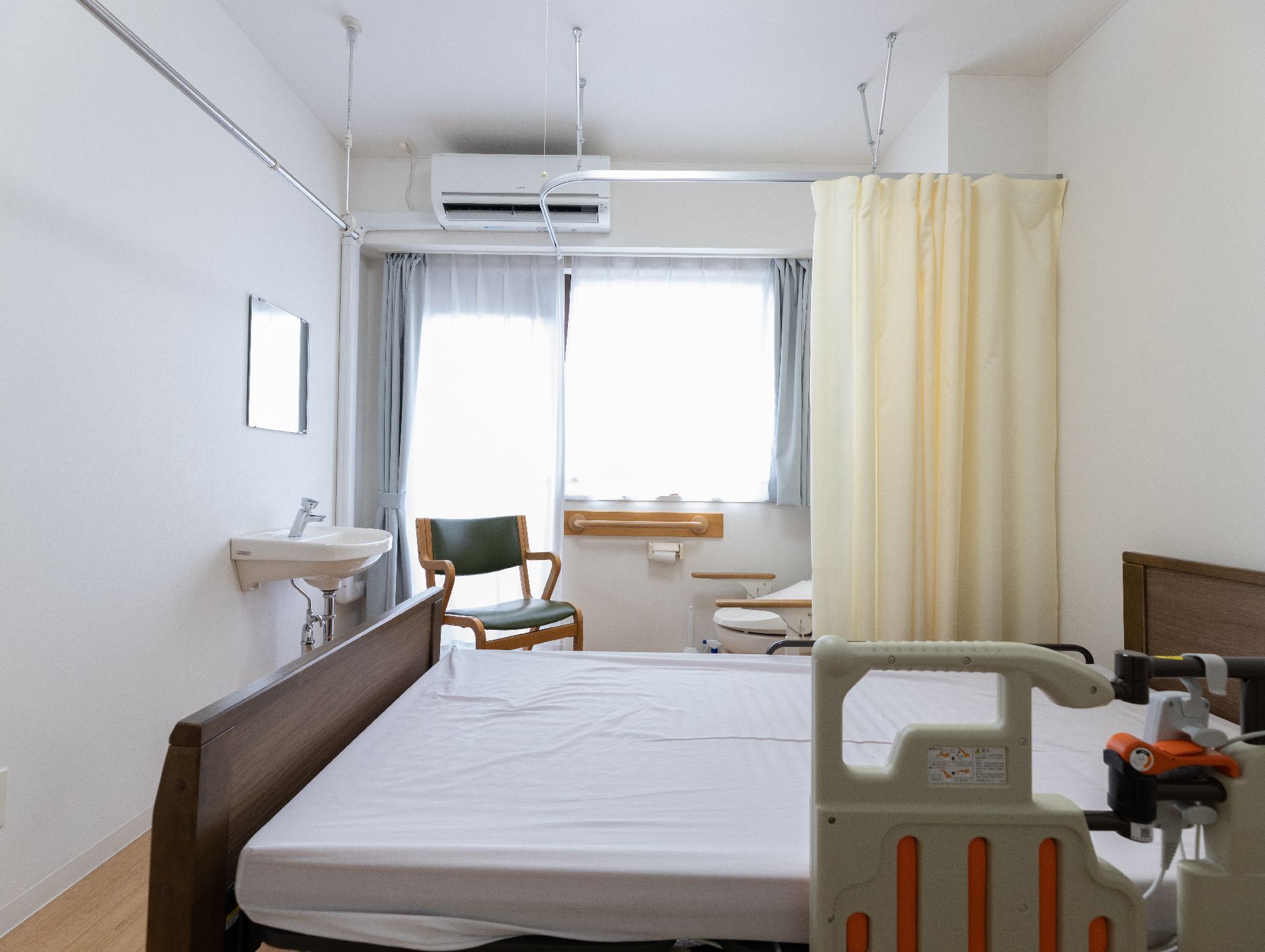 大きな窓から光が注ぎ、介護ベッドや椅子が置かれている居室