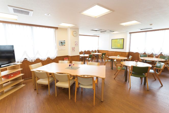 椅子に腰かけながら水風船釣りを楽しむ入居者と見守るスタッフ