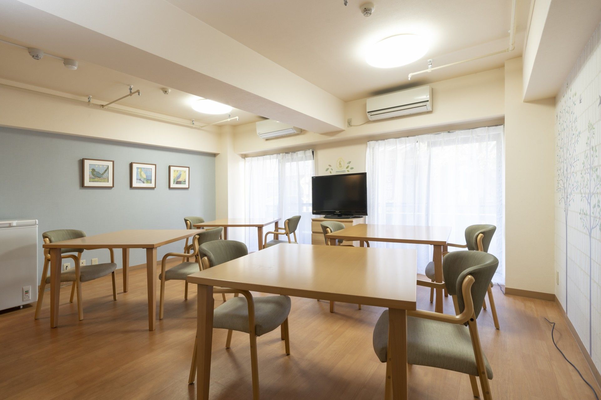 椅子がセットされたダイニングテーブル、ソファー、テレビが置かれたＬ字型の食堂