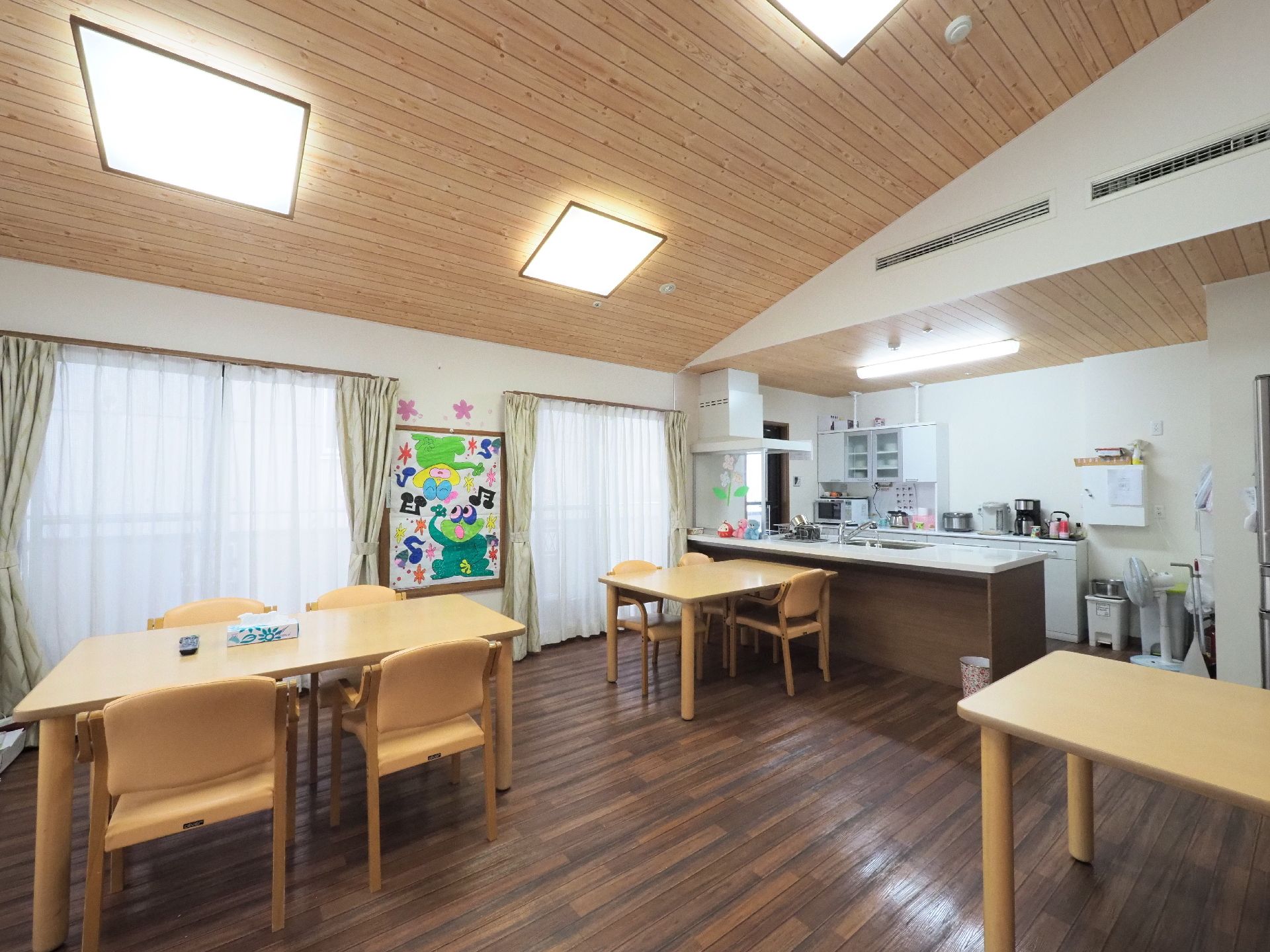 明るいダイニングルームとなるように、陽の光が差し込む大きな窓を設置している。また天井にはたくさんの照明器具が取り付けられている。