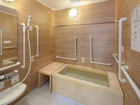 「グランダ南麻布」の5F浴室。ヒノキ香る湯船に、安全に配慮した介助手すり、シャワーチェアが付いている。